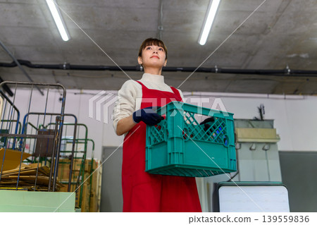 A woman carries a container. A woman carries a container. 139559836