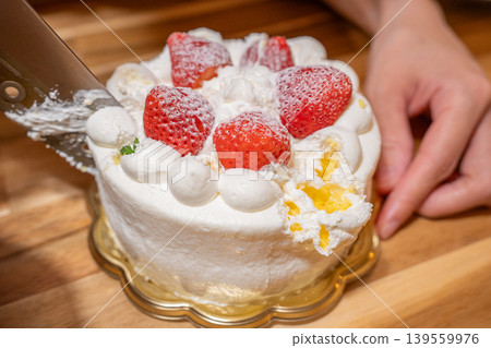 The scene of someone diligently cutting a cake, getting a little messy in the process. 139559976