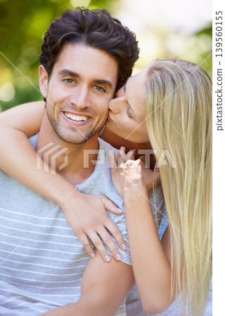 Couple, hug and woman kiss man in park with smile, love and commitment in healthy relationship. People on date outdoor, portrait and care with trust, partner and bonding together for marriage 139560155