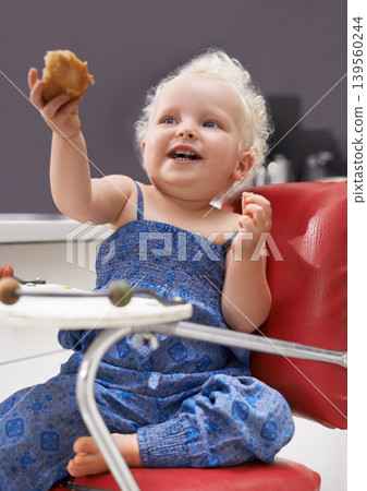 Child, high chair and eating muffin, food and breakfast sweets at home in kitchen. Young kid, hungry toddler and cupcake dessert, sugar and pastry snack for happy cute girl in house in the morning Child, high chair and eating muffin, food and breakfast sweets at home in kitchen. Young kid, hungry toddler and cupcake dessert, sugar and pastry snack for happy cute girl in house in the morning 139560244