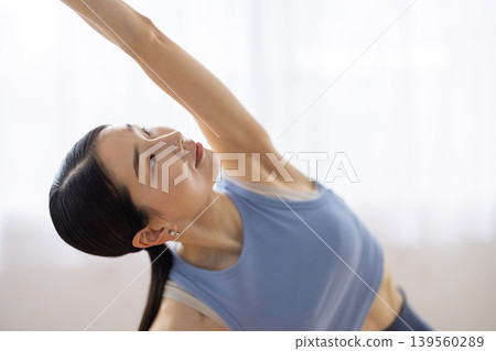 一位日本女子在明亮的窗邊，於瑜珈墊上做側角式瑜珈。 139560289