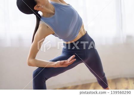 一位日本女子在明亮的窗邊，於瑜珈墊上做側角式瑜珈。 139560290