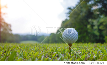 Golf ball on tee in a beautiful golf course with morning sunshine. Golf ball on tee in a beautiful golf course with morning sunshine. 139560421