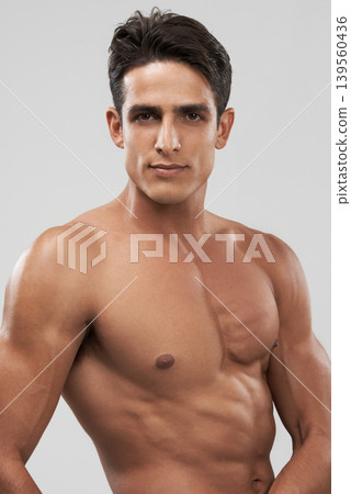 Man, shirtless and portrait or bodybuilder pride in studio, abs and fitness by gray background. Male person, confident and strong core or muscular abdomen, face and results or progress from exercise Man, shirtless and portrait or bodybuilder pride in studio, abs and fitness by gray background. Male person, confident and strong core or muscular abdomen, face and results or progress from exercise 139560436