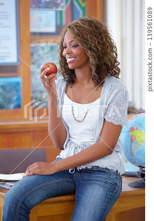 Happy black woman, teacher and eating apple for natural diet, nutrition or food for snack in classroom. African female person or educator smile with red organic fruit for health and wellness in class Happy black woman, teacher and eating apple for natural diet, nutrition or food for snack in classroom. African female person or educator smile with red organic fruit for health and wellness in class 139561089
