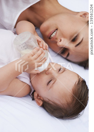 Above, care and a mother with a baby and milk for nutrition, health and growth development. Morning, family and a young mom and child with a bottle in the bedroom of a house for food and a drink Above, care and a mother with a baby and milk for nutrition, health and growth development. Morning, family and a young mom and child with a bottle in the bedroom of a house for food and a drink 139561204