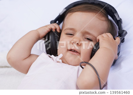 Baby, headphones and listening to music for fun, streaming radio and podcast on bed at home. Child, relax and hearing sound for child development or learning, toddler and calming playlist for audio Baby, headphones and listening to music for fun, streaming radio and podcast on bed at home. Child, relax and hearing sound for child development or learning, toddler and calming playlist for audio 139561460