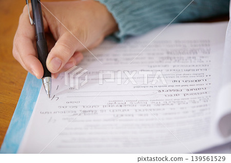 Hand, pen and teacher mark paper, education and learning with closeup of test or assignment on desk in classroom. Person in class, exam or project, grade and feedback with results, notes and writing 139561529
