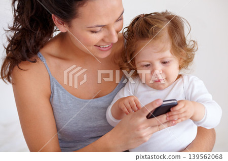 Cellphone, playing and mother with baby on bed for bonding and watching video on social media together. Happy, love and young mom scroll on a phone with girl child, kid or toddler in bedroom at home Cellphone, playing and mother with baby on bed for bonding and watching video on social media together. Happy, love and young mom scroll on a phone with girl child, kid or toddler in bedroom at home 139562068