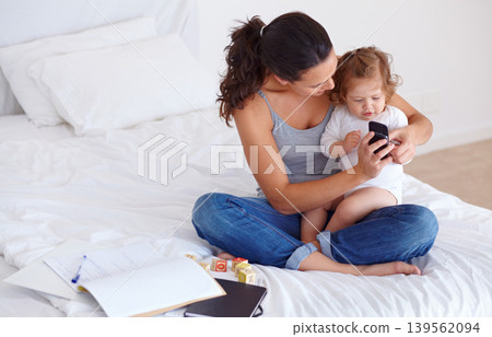 Phone, playing and mother with baby on bed for bonding and watching video on social media together. Happy, love and young mom scroll on cellphone with girl child, kid or toddler in bedroom at home. Phone, playing and mother with baby on bed for bonding and watching video on social media together. Happy, love and young mom scroll on cellphone with girl child, kid or toddler in bedroom at home. 139562094