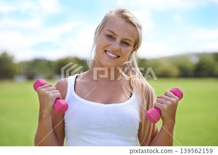 Happy woman, portrait and dumbbells for fitness, workout or outdoor exercise in nature. Active female person or blonde smile for weightlifting or training in health and wellness on green grass field Happy woman, portrait and dumbbells for fitness, workout or outdoor exercise in nature. Active female person or blonde smile for weightlifting or training in health and wellness on green grass field 139562159