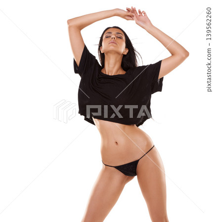 Dancing, beauty and woman in underwear in studio listening to music, playlist or radio for fun. Attractive, moving and female person enjoying a song with casual style and panties by white background. 139562260
