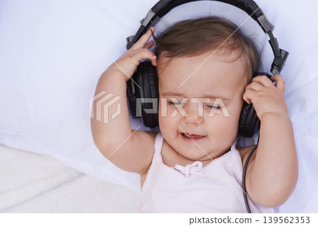 Baby, headphones and streaming music to relax, radio and listening to podcast on bed at home. Girl, kid and hearing sound for child development or learning, toddler and calming playlist for audio Baby, headphones and streaming music to relax, radio and listening to podcast on bed at home. Girl, kid and hearing sound for child development or learning, toddler and calming playlist for audio 139562353