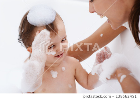 Baby, bath and mother laughing in a bathroom with cleaning, foam and help with love and support. Care, mom and young child with soap in a home with bonding and washing for wellness and hygiene Baby, bath and mother laughing in a bathroom with cleaning, foam and help with love and support. Care, mom and young child with soap in a home with bonding and washing for wellness and hygiene 139562451