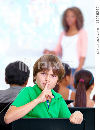 Portrait, student or child in classroom with hush, gossip or fingers on lips for quiet learning. Sign, study or boy learner with whisper or shush gesture for rumor, loud noise or silence in school 139562494