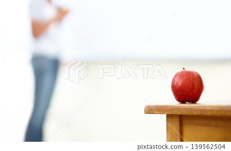 Red apple, teacher and desk in classroom for natural diet, snack or nutrition with fiber on table. Closeup of fresh organic fruit or food for eating, health and wellness on mockup space at school Red apple, teacher and desk in classroom for natural diet, snack or nutrition with fiber on table. Closeup of fresh organic fruit or food for eating, health and wellness on mockup space at school 139562504