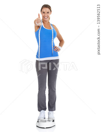 Woman thumbs up, diet scale and measure tape in studio for fitness, weight loss or health goals, like and yes. Portrait of happy model with workout results, success or feedback on a white background Woman thumbs up, diet scale and measure tape in studio for fitness, weight loss or health goals, like and yes. Portrait of happy model with workout results, success or feedback on a white background 139562513