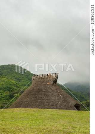 一座孤零零地矗立在霧氣瀰漫的草原上的半地穴式房屋。 一座孤零零地矗立在霧氣瀰漫的草原上的半地穴式房屋。 139562531
