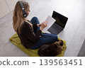 Woman studies with laptop and cat on a cozy mat in a modern home office 139563451