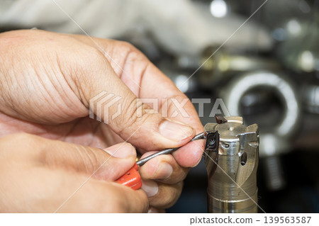Close-up of replacing a tungsten carbide chip insert on an indexable cutting tool for CNC machine operation. Close-up of replacing a tungsten carbide chip insert on an indexable cutting tool for CNC machine operation. 139563587