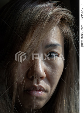 A moment of raw, unvarnished intimacy. Soft, directional light carves deep shadows across her face, transforming it into a landscape of quiet emotion. Through a veil of honey-hued hair, a single dark A moment of raw, unvarnished intimacy. Soft, directional light carves deep shadows across her face, transforming it into a landscape of quiet emotion. Through a veil of honey-hued hair, a single dark 139563702