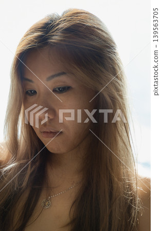 A dreamlike radiance bathes this portrait, where the woman stands in a moment of hushed grace. Light pours through her honeyed hair, turning silk-like strands into a delicate glow that softens every 139563705