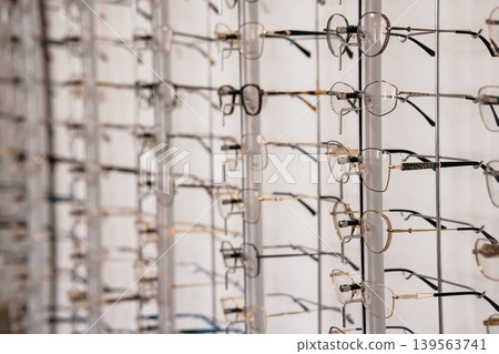 Collection of stylish eyeglasses frames hanging on a modern display rack in an optical shop with clean white background Collection of stylish eyeglasses frames hanging on a modern display rack in an optical shop with clean white background 139563741