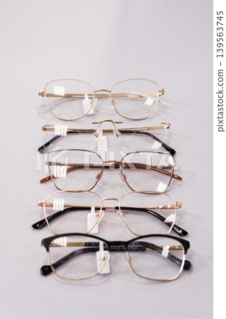 Five fashion eyeglasses stacked vertically on white background, gold and black frames, optical concept, flat lay product photography for vision care design Five fashion eyeglasses stacked vertically on white background, gold and black frames, optical concept, flat lay product photography for vision care design 139563745