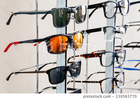 Assorted Spectacles Display Stand In Optometry Store Interior With White Wall Background And Colorful Lenses For Vision Correction Assorted Spectacles Display Stand In Optometry Store Interior With White Wall Background And Colorful Lenses For Vision Correction 139563770