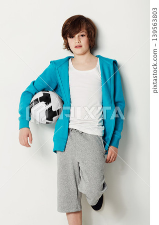 Football, casual and portrait of teenager in a studio for sports training or exercise with style. Serious, fashion and boy kid athlete with soccer confidence and trendy outfit by white background. Football, casual and portrait of teenager in a studio for sports training or exercise with style. Serious, fashion and boy kid athlete with soccer confidence and trendy outfit by white background. 139563803