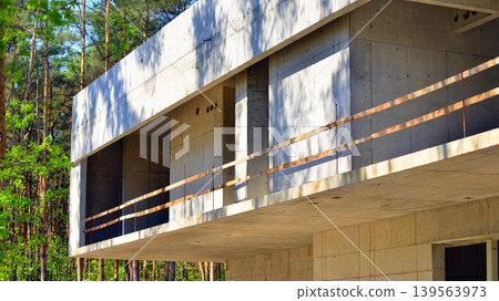 An abandoned concrete building under construction surrounded by a forest. An unfinished two-story modernist structure. An abandoned concrete building under construction surrounded by a forest. An unfinished two-story modernist structure. 139563973