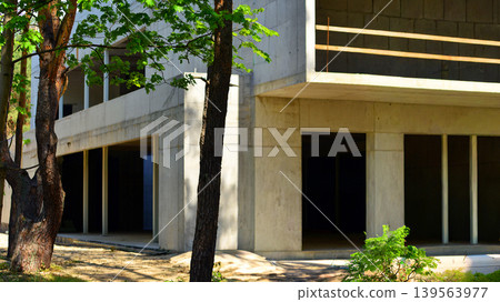 An abandoned concrete building under construction surrounded by a forest. An unfinished two-story modernist structure. An abandoned concrete building under construction surrounded by a forest. An unfinished two-story modernist structure. 139563977