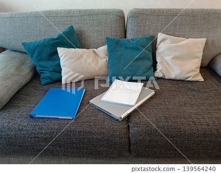 Laptop and Notebook on Grey Sofa with Cushions Laptop and Notebook on Grey Sofa with Cushions 139564240