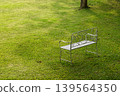 Vintage white metal garden chair on an empty green lawn in a peaceful backyard garden 139564350