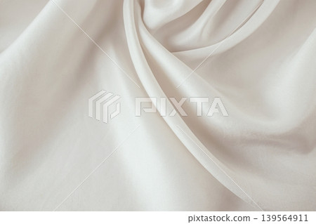 Beige silk fabric texture background. Close-up of elegant light beige silk fabric with soft folds and draperies. Beige silk fabric texture background. Close-up of elegant light beige silk fabric with soft folds and draperies. 139564911