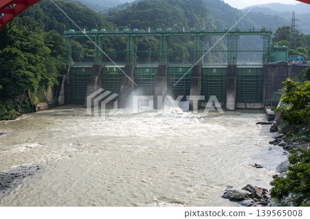 Water being released from a dam nestled in a lush, mountainous area. Water being released from a dam nestled in a lush, mountainous area. 139565008