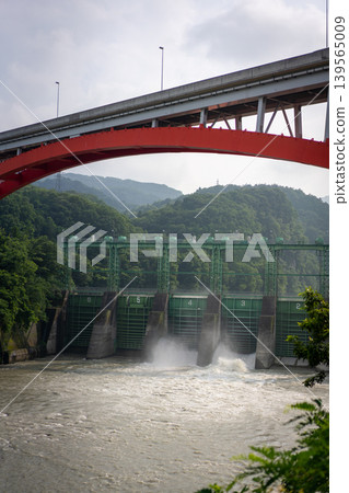 Dam discharge and a view of a red bridge Dam discharge and a view of a red bridge 139565009