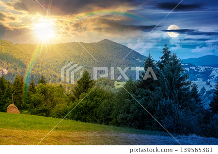 day meet night on mountain hay field. sun and moon over alpine countryside summer landscape with green valley behind the woods on the grassy slope at twilight. cloudy sky. epic highland background day meet night on mountain hay field. sun and moon over alpine countryside summer landscape with green valley behind the woods on the grassy slope at twilight. cloudy sky. epic highland background 139565381