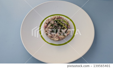 Fish tartare with chopped scallion and pickled onion on a white plate on a blue table Fish tartare with chopped scallion and pickled onion on a white plate on a blue table 139565401