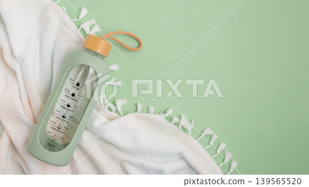 Water bottle and towel on a light green background. 139565520