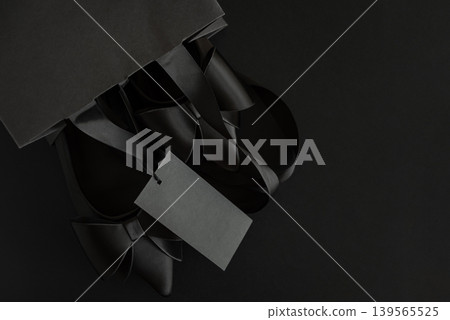 Black Pointed Toe Shoes with Blank Tag into Paper Package on Black Background Black Pointed Toe Shoes with Blank Tag into Paper Package on Black Background 139565525