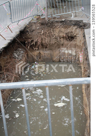 The hole in the road was created to repair underground utilities. 139565528