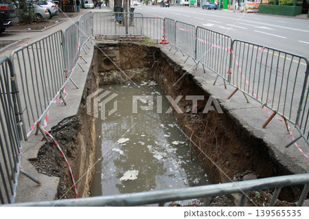 The hole in the road was created to repair underground utilities. 139565535