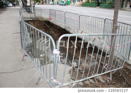The hole in the road was created to repair underground utilities. The hole in the road was created to repair underground utilities. 139565537