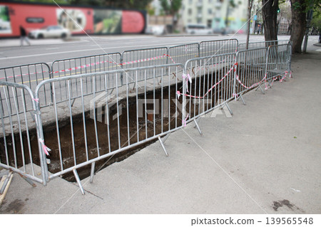 The hole in the road was created to repair underground utilities. 139565548