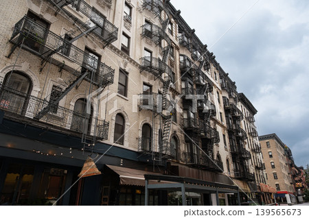 New york, usa august 17,2024. New york city residential and commercial buildings featuring classic brick architecture and intricate iron fire escapes under a cloudy sky 139565673