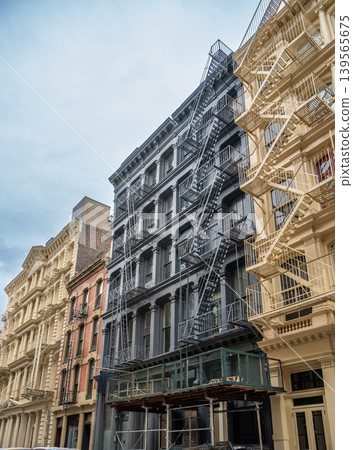 New york, usa august 17,2024. Soho buildings showcasing historic cast iron architecture and external fire escapes under an overcast sky creating a classic urban scene New york, usa august 17,2024. Soho buildings showcasing historic cast iron architecture and external fire escapes under an overcast sky creating a classic urban scene 139565675