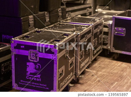 Professional flight cases and black trunks stacked backstage, containing stage equipment and concert electronics Professional flight cases and black trunks stacked backstage, containing stage equipment and concert electronics 139565897