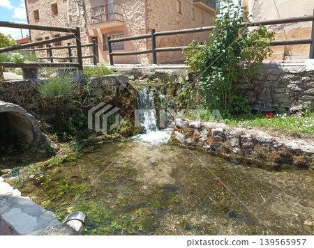 Small waterfall and crystal clear pond in a traditional Spanish village. Small waterfall and crystal clear pond in a traditional Spanish village. 139565957