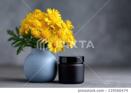 Italicum flowers with chamomile in a blue vase next to a black container 139566474